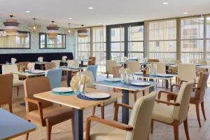a restaurant with tables and chairs and windows at Quality Aparthotel Voiron in Voiron