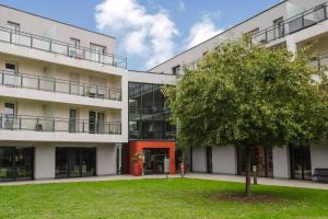an apartment building with a tree in front of it at Quality Aparthotel St-Berthevin Laval in Saint-Berthevin-sur-Vicoin