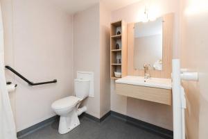 a bathroom with a toilet and a sink at Quality Aparthotel St-Berthevin Laval in Saint-Berthevin-sur-Vicoin +13 photos