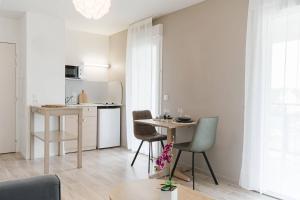 a kitchen with a table and chairs in a room at Quality Aparthotel St-Berthevin Laval in Saint-Berthevin-sur-Vicoin