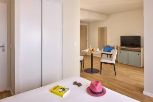 a room with a bed and a table with a hat at Quality Aparthotel Rouen in Rouen