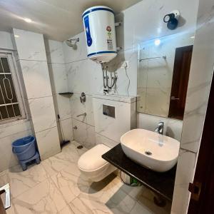 a white bathroom with a toilet and a sink at Kaisha Himalayan View in Shimla