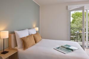 a bedroom with a bed with a book on it at Quality Aparthotel Plerin Saint Brieuc in Plérin