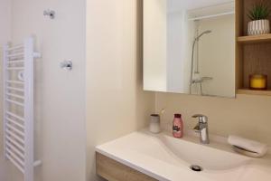 a white bathroom with a sink and a mirror at Quality Aparthotel Plerin Saint Brieuc in Plérin +31 photos