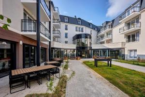 a building with benches and tables in the courtyard at Quality Aparthotel Cherbourg in Cherbourg en Cotentin