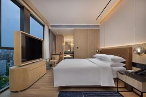 a bedroom with a white bed and a flat screen tv at Four Points by Sheraton Huzhou in Huzhou