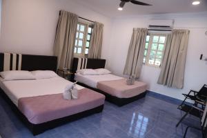 a bedroom with two beds and two windows at Penyu Bari in Setiu