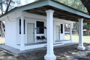 a white cottage with two chairs on a porch at Penyu Bari in Setiu