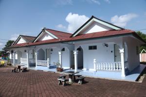 a white building with benches in front of it at Penyu Bari in Setiu