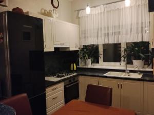 a kitchen with white cabinets and a black refrigerator at Дом in Odesa