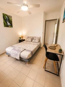 a bedroom with a bed and a table and a desk at Le Cocon de Mont-Vert in Le Robert