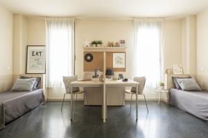 a room with a desk and two beds and a table at Residencia Universitaria Giner de Los Ríos in Alcalá de Henares