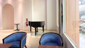 a room with a piano and two blue chairs at Paul and Pam Hotel Bangkok in Bang Kapi +26 photos