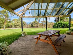a wooden picnic table sitting under a pavilion at The Lakeside Retreat in Perth