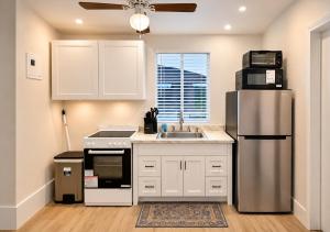 eine Küche mit weißen Schränken und einem Edelstahlkühlschrank in der Unterkunft Modern Cozy Studio in Pinewood + 5 Fotos