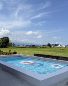 a large swimming pool with a field in the background at 根本家民宿 in Dayi
