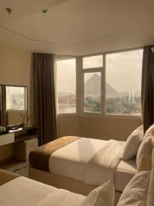 a hotel room with two beds and a large window at Wonders Pyramids Hotel in Cairo