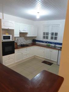 a kitchen with white cabinets and a black appliance at Villa Le Balisier in Le Lamentin