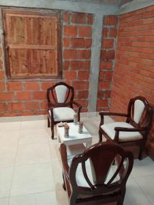 three chairs and a table in a room with a brick wall at Posada El Encanto in Nuquí