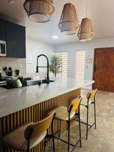 a kitchen with a counter and four stools at Stillness Suite - Tamarindo - Pinilla - Avellanas - Pool - BBQ in San José Pinilla