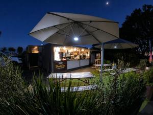 a white umbrella and two chairs and a food truck at BeachBox Boutique Accommodation in Coopers Beach +6 photos