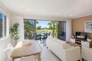 a living room with a white couch and a table at Seachange Apartments Merimbula in Merimbula