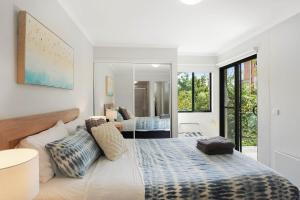 a bedroom with a large bed and a mirror at Seachange Apartments Merimbula in Merimbula