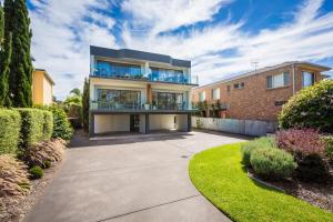 a large house with a balcony on top of a driveway at Seachange Apartments Merimbula in Merimbula