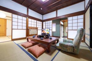 a living room with a table and chairs and windows at 湊の宿あまね in Hitachinaka