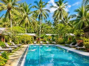 a swimming pool with chaise lounge chairs and palm trees at Traveller's Home Safari Resort in Udawalawe