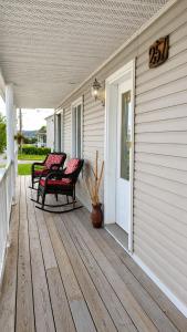 a porch with two chairs on a house at Chez nous ailleurs in Sainte-Anne-des-Monts