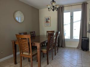 a dining room with a table and chairs and a clock at Chez nous ailleurs in Sainte-Anne-des-Monts