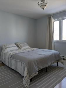 a white bedroom with a bed and a window at Chez nous ailleurs in Sainte-Anne-des-Monts +7 photos