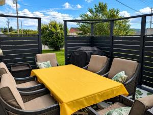 a yellow table and chairs on a patio at Chez nous ailleurs in Sainte-Anne-des-Monts