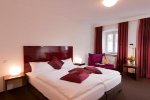 a bedroom with a large bed with red curtains at Hotel Bergbauer in Neuburg an der Donau
