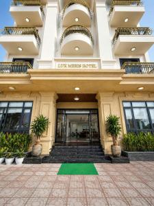 a building with a green lawn in front of it at Lux Meris Hotel in Nhượng Bạn