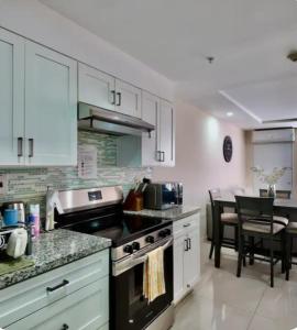 a kitchen with white cabinets and a stove top oven at Royal Estate in Portmore +3 photos