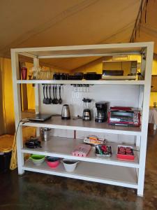 a white shelf with utensils in a kitchen at GuanaGlamp in Tamarindo