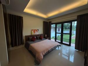 a bedroom with a bed and a large window at Villa Tara Khaolak in Khao Lak