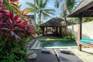a villa with a swimming pool in a garden at Temuku Ubud Villas in Ubud