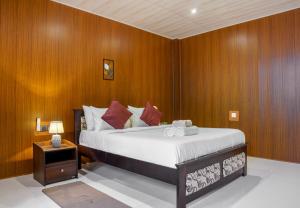 a bedroom with a large bed with wooden walls at Rock View Cottage in Ella