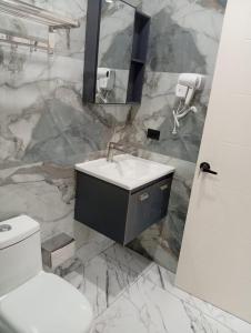 a marble bathroom with a sink and a toilet at Hotel Herradura in Herradura