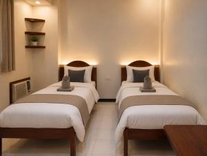 two beds in a hotel room with white walls at LIV Coron in Coron +8 photos