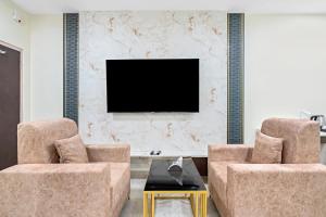 a living room with two chairs and a tv at Hotel Skyland Khammam in Khammam