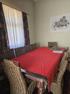 a dining room with a red table with wicker chairs at Mukamba Holiday Accommodation in Livingstone +4 photos