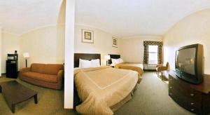 a hotel room with two beds and a flat screen tv at Quality Suites Jeffersonville - Louisville North in Clarksville