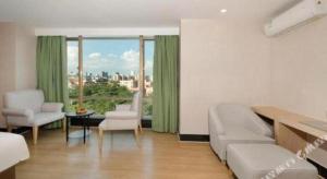 a living room with a couch and chairs and a large window at Cheerful Hotel in Nanhai