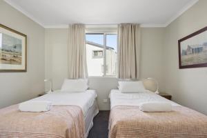 two beds in a room with a window at Horizons 404 in Jindabyne +22 photos