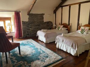 a bedroom with two beds and a stone wall at 16th Century Devon Farmhouse Stunning Views in Winkleigh