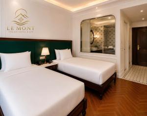 a hotel room with two beds and a mirror at Le Mont Yên Bái in Yên Bái